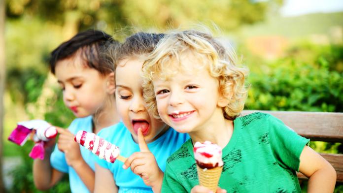 Little girl and boys eating ice cream in the park.