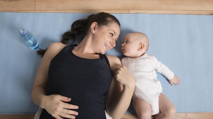 Beautiful young woman exercising with her baby boy