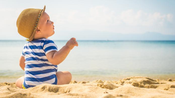 Little baby boy sitting on the sand