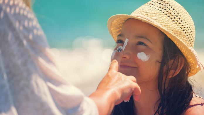 Young Mother Applying Suntan Lotion On Daughter's Face