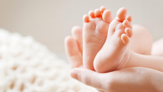 Baby feet in mother hands. Mom and her Child.