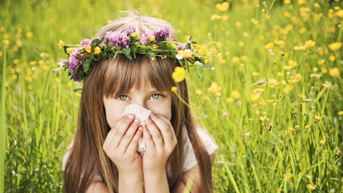 Little girl in grass cleaning her nose