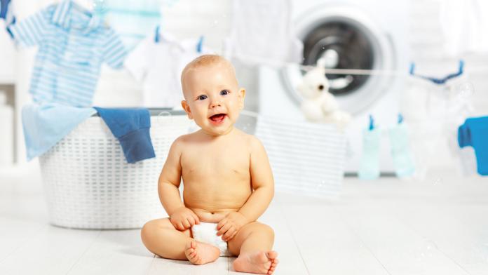 fun happy baby boy to wash clothes and laughs in laundry