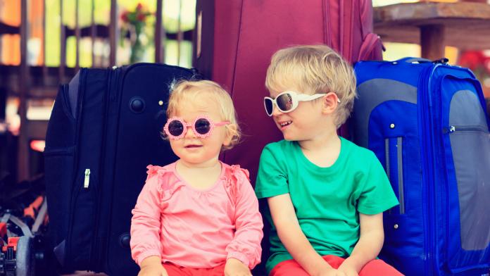 kids sitting on suitcases ready to travel