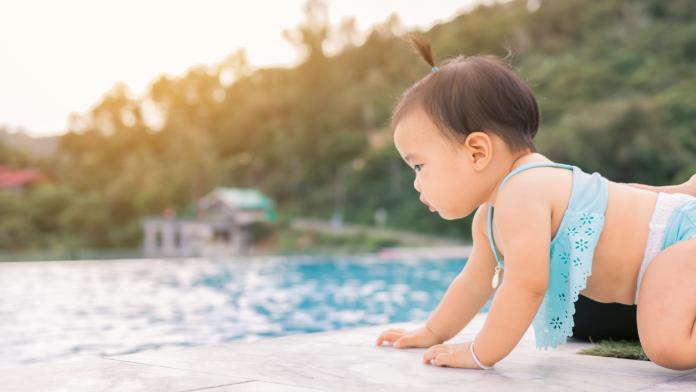 Baby infant tries to crawl down to the pool alone with danger.