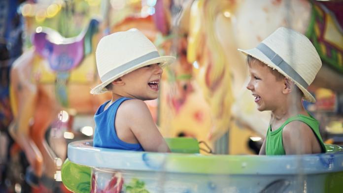 Little brothers having fun on carousel.
