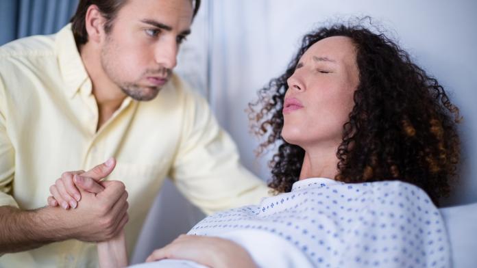 Man comforting pregnant woman during labor in ward