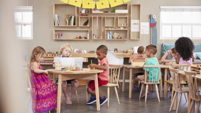 Wide Angle Shot Of Pupils Working At Tables In Montessori School