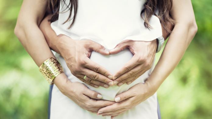 Couple Hand Make Heart Symbol on Pregnant Wife Stomach