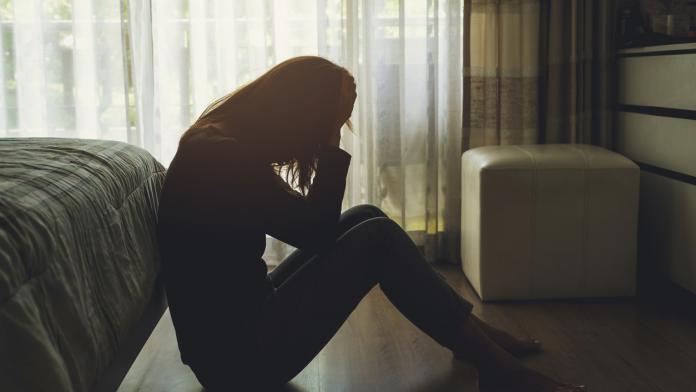 depressed woman sitting in the dark bedroom