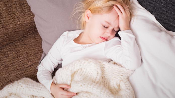Little child being sick and holding her hand on forehead
