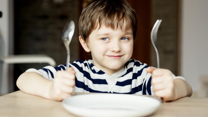 Happy little boy waiting for dinner.
