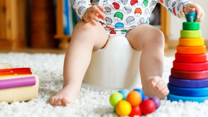 Closeup of cute little 12 months old toddler baby girl child sitting on potty.