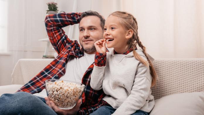 father and daughter eating popcorn