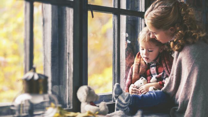 family mother and child look out window on rainy autumn