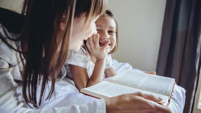 Mother and daughter reading book in bed