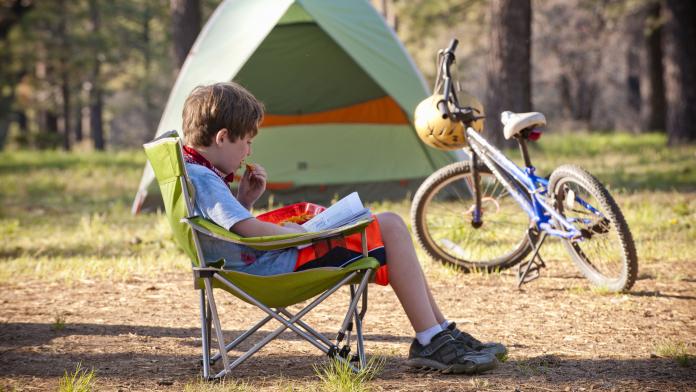 Caucasian boy reading book at campground
