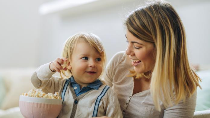Smiling little boy and his mother eating popcorn.