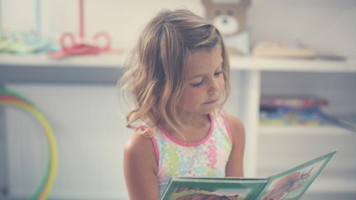 Little girl in playground. Little girl reading picture book.