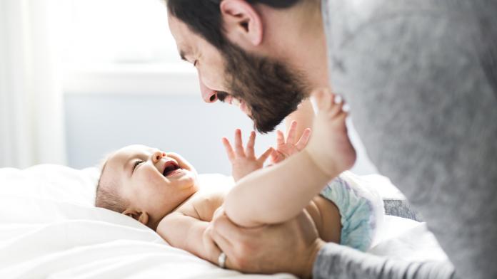 happy father playing with adorable baby in bedroom