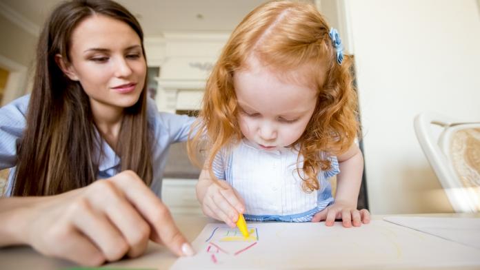 Concentrated little daughter painting with mother