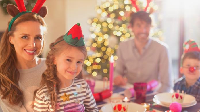 Portrait smiling mother and daughter wearing costume reindeer antlers at Christmas dinner table