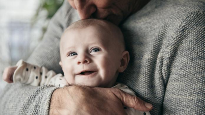 Mature father kissing laughing baby on its head
