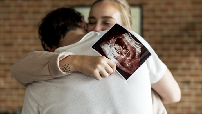 White couple with baby ultrasound photo