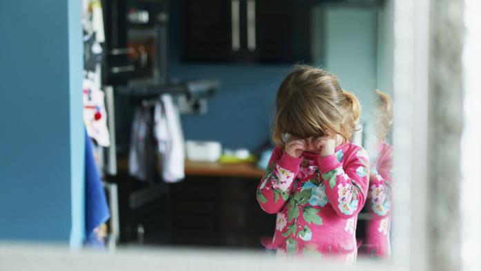 Reflection of upset girl rubbing eyes in mirror