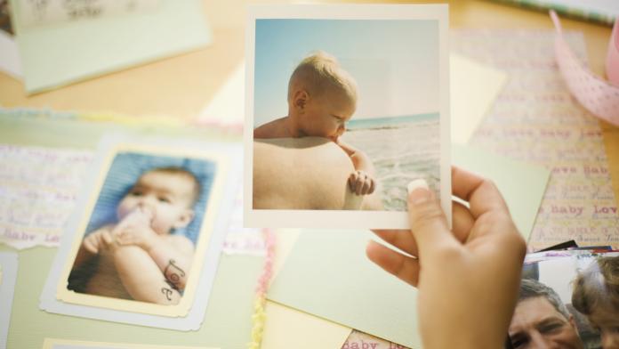 Woman holding baby picture for scrapbook Babyherinneringen