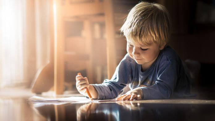Boy lying on the floor with a coloring book kind met autisme