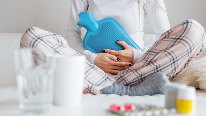 Woman with hot water bottle healing stomach pain menstruatie