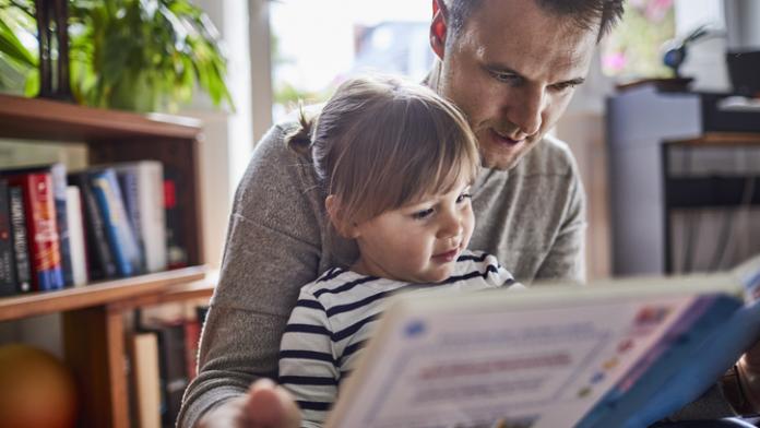 Father reading book with daughter at home lezen