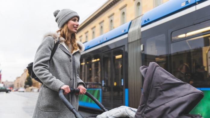 Mid adult woman getting on bus with baby carriage kinderwagen