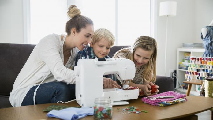 Mother and children sewing at sewing machine