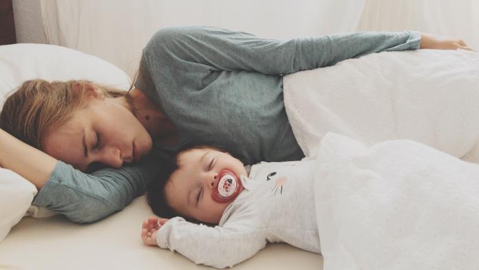 Mother And Son Sleeping On Bed At Home