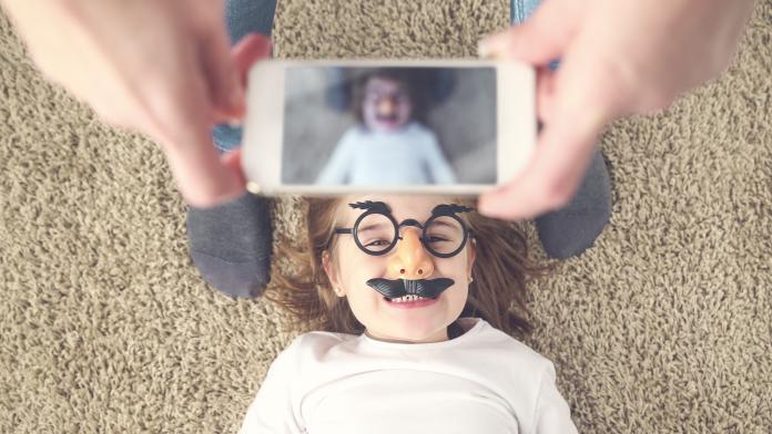 Mother taking photo of her daughter with smartphone kleuter in huis