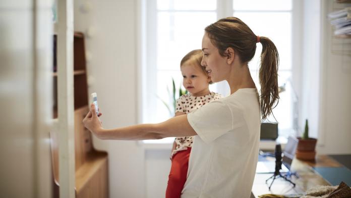Female influencer taking selfie with daughter through smart phone at home