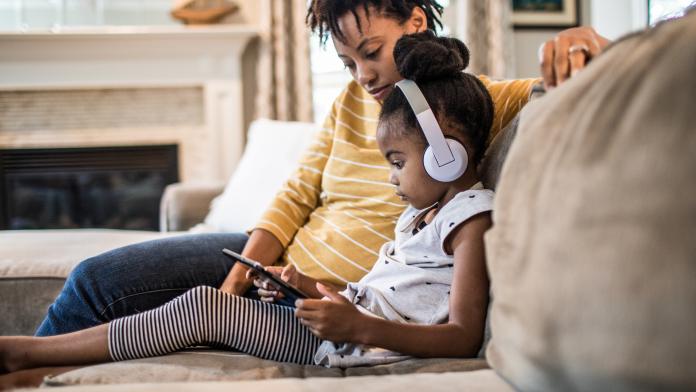 Mother and daughter on couch using tablet