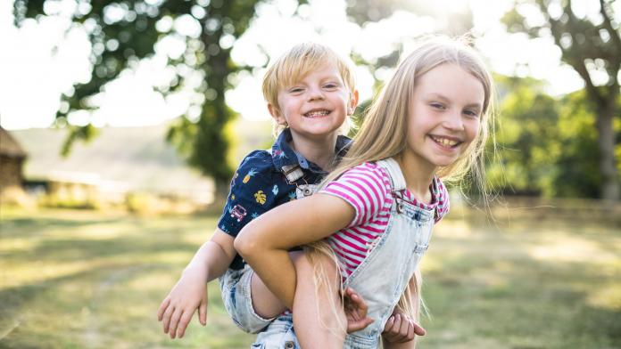 Girl giving her brother a piggyback ride ontwikkeling van emotionele intelligentie bij kinderen