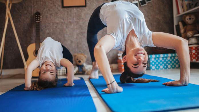 Mother and daughter working out together doing exercise at home thuis-workouts voor kinderen