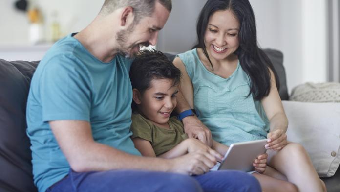 Smiling family looking at digital tablet in house tweetalig opvoeden