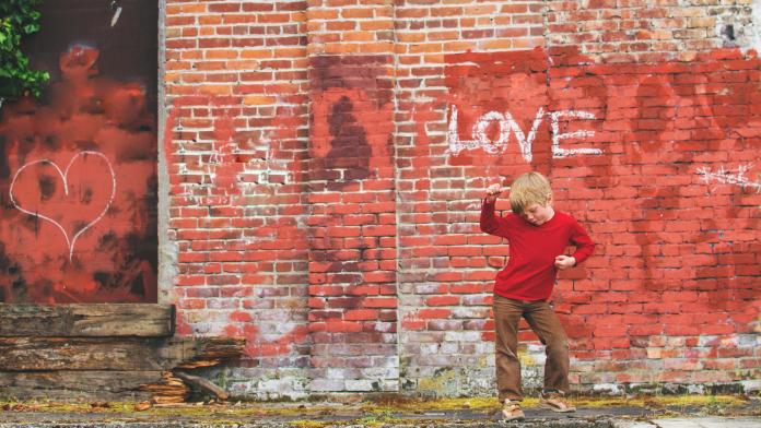Boy posing in front of wall with graffiti