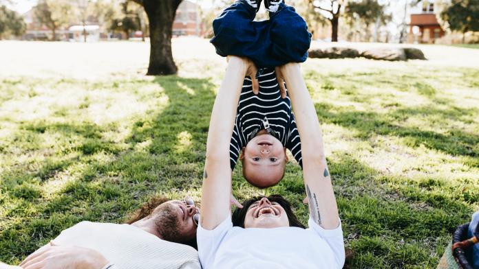 Couple with baby on picnic blanket in park