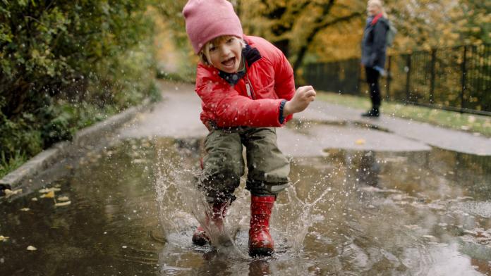 Playful boy splashing water in puddle on road