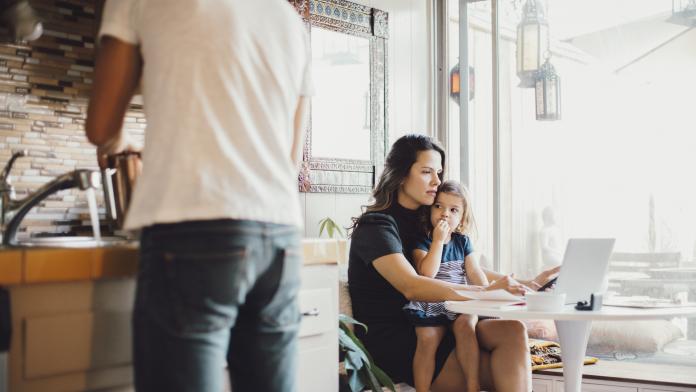 Mother working on laptop while daughter looking at father standing in kitchen thuiswerkende ouders