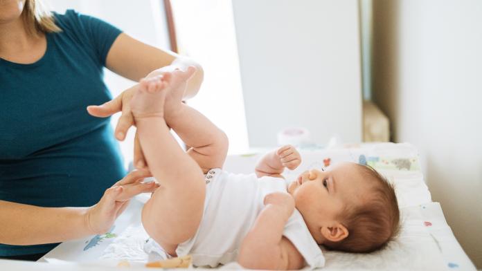 Millennial mother and newborn baby girl - changing diapers