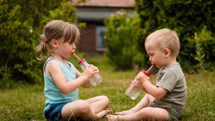 Siblings sitting together in backyard