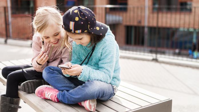 Girls (8-9) using mobile phone