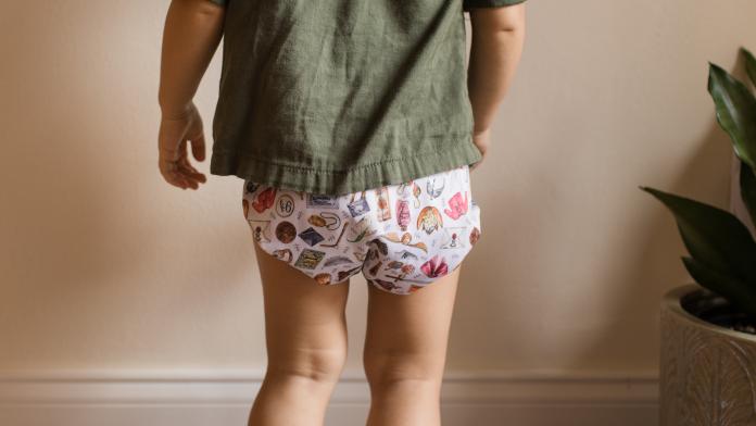 A 19-Month-Old Toddler Girl in a Reusable Cloth Diaper and a Olive Green Shirt bedplassen herbruikbare luiers optrekbroekjes